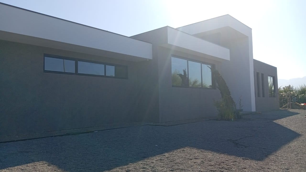 Casa moderna de líneas rectas con muros de hormigón y ventanales, construida por Valcorp