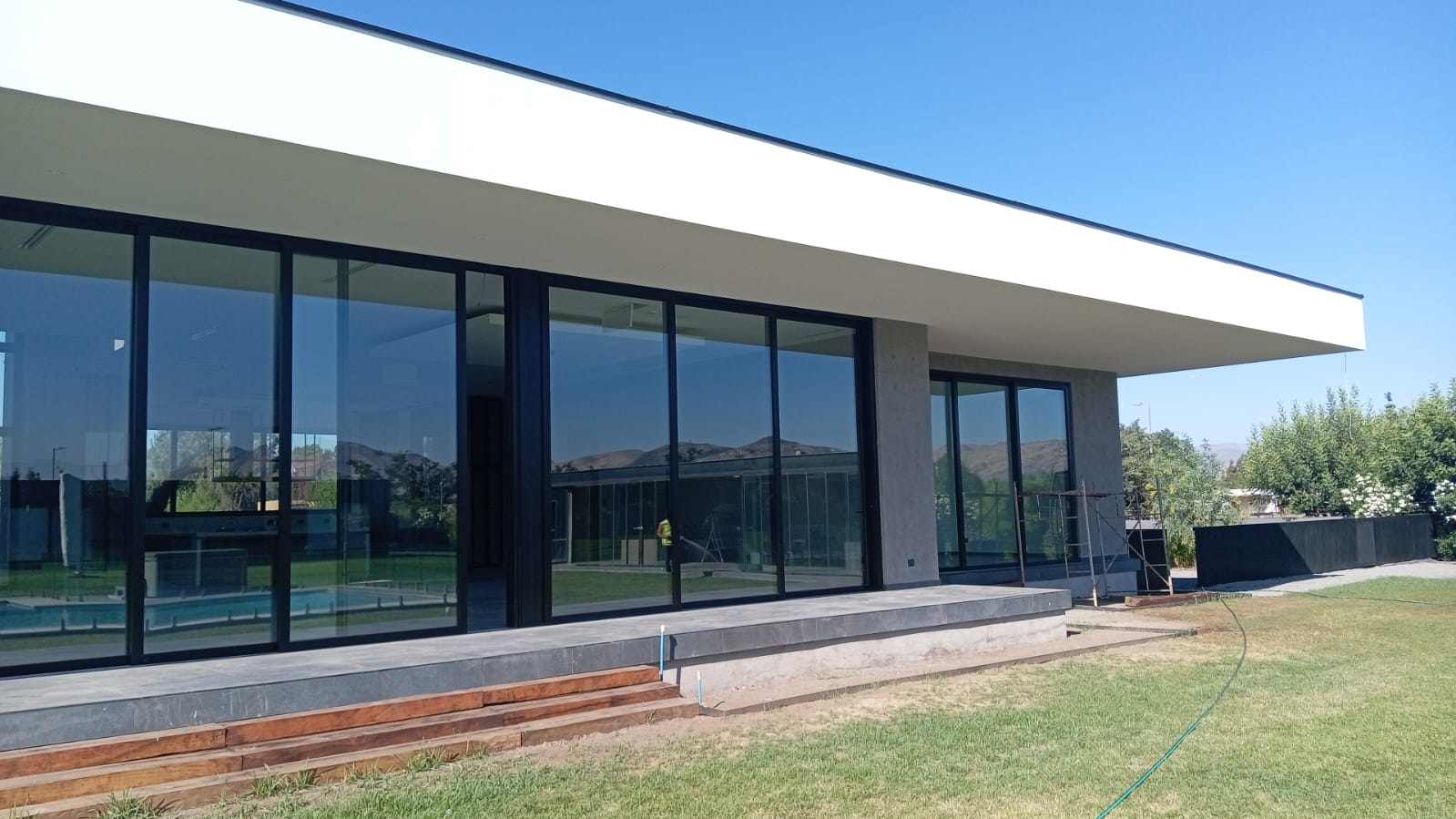 Casa moderna con estructura de hormigón, grandes ventanales y terraza de madera, construida por Valcorp