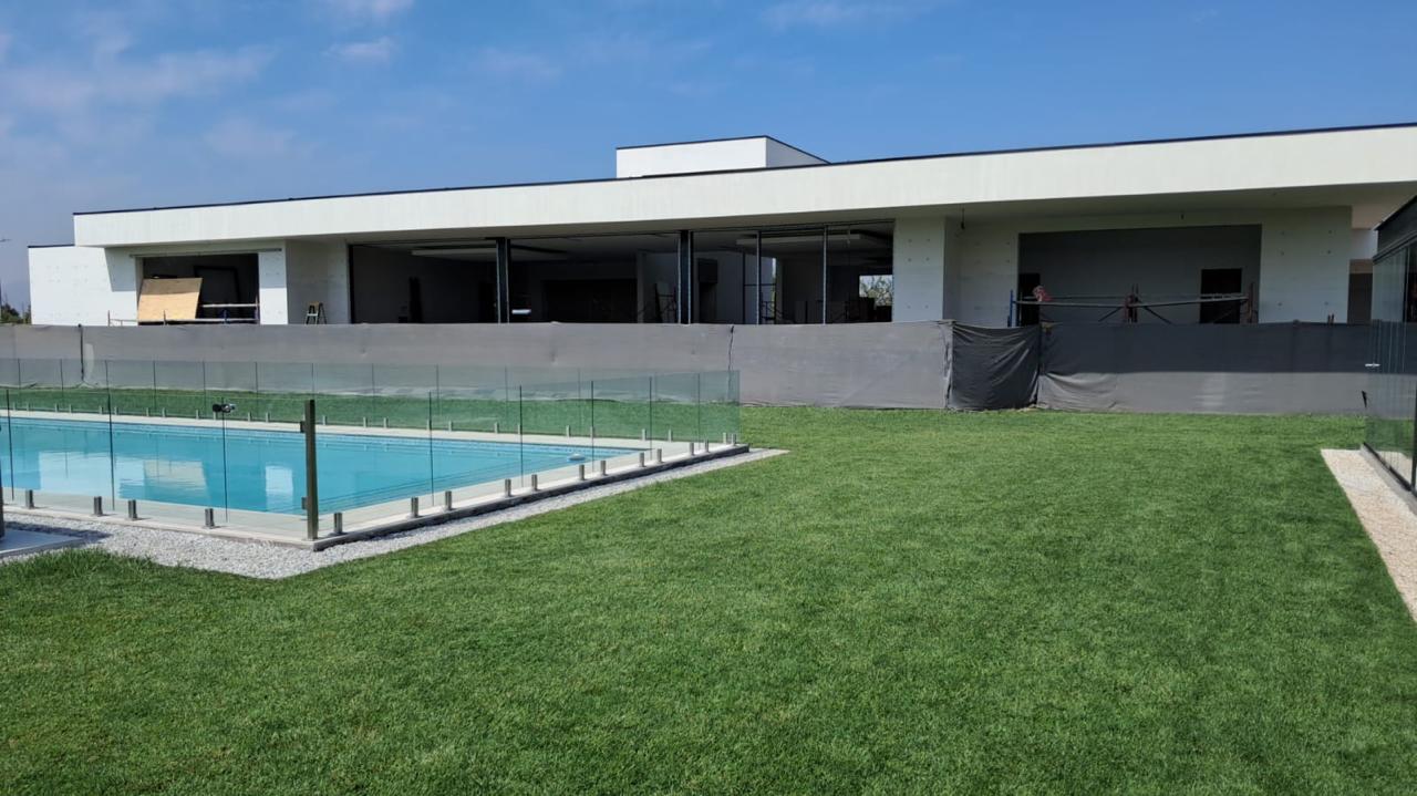 Casa moderna en construcción con piscina terminada y cierre de cristal, proyecto integral de Valcorp