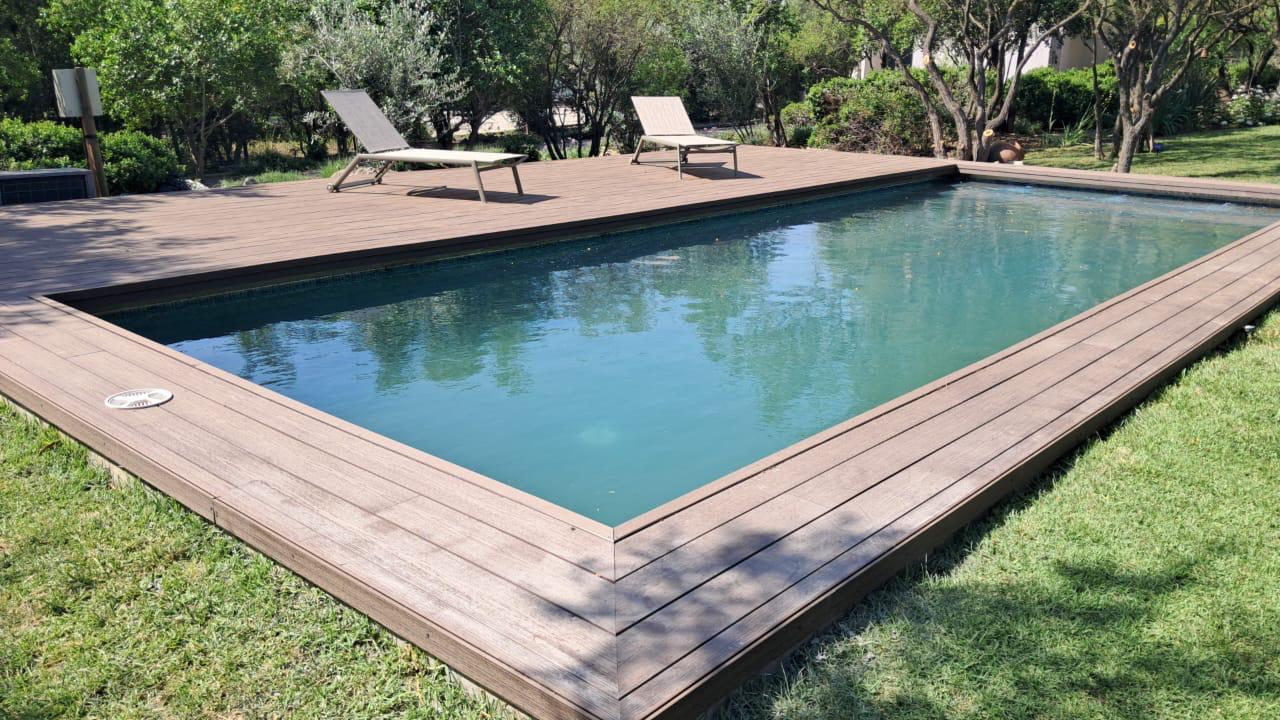 Piscina terminada con deck de madera perimetral y jardín, obra de Valcorp