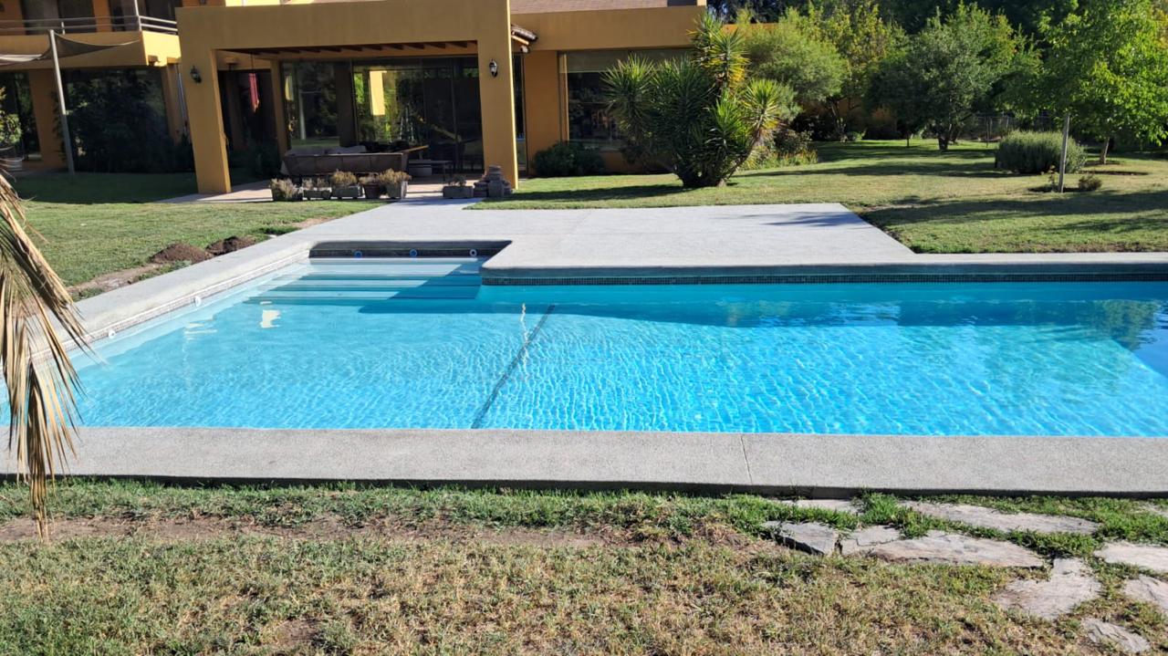 Piscina de hormigón celeste con escalones interiores y solera de hormigón lavado