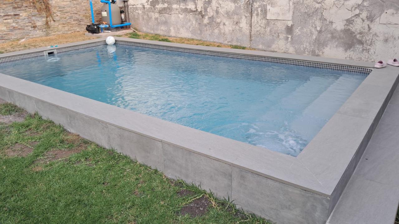 Piscina de hormigón con borde de piedra gris y equipos de filtrado instalados